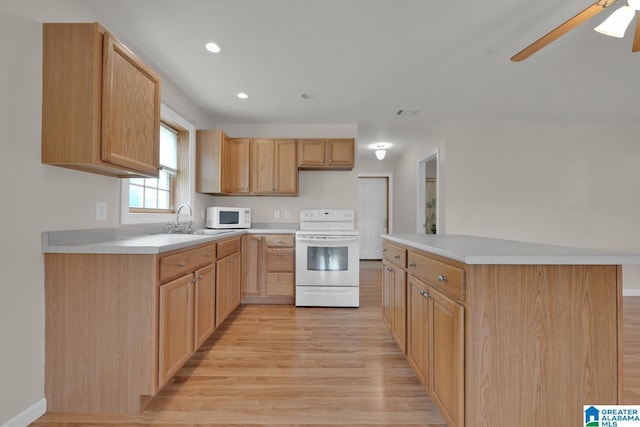 kitchen featuring light wood-style floors, a sink, white appliances, and light countertops