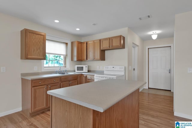 kitchen featuring visible vents, a sink, baseboards, light wood-style floors, and white appliances