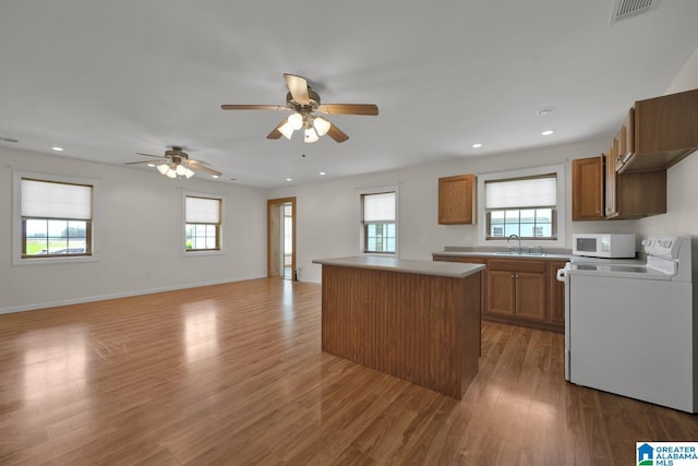 kitchen with electric range, white microwave, a center island, light wood-type flooring, and visible vents