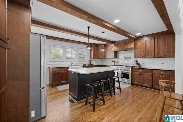 kitchen with light wood-style floors, a breakfast bar area, tasteful backsplash, a sink, and appliances with stainless steel finishes