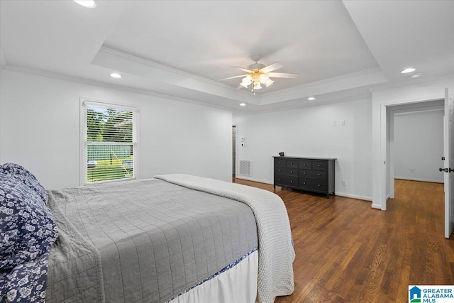 bedroom with crown molding, a tray ceiling, recessed lighting, and wood finished floors