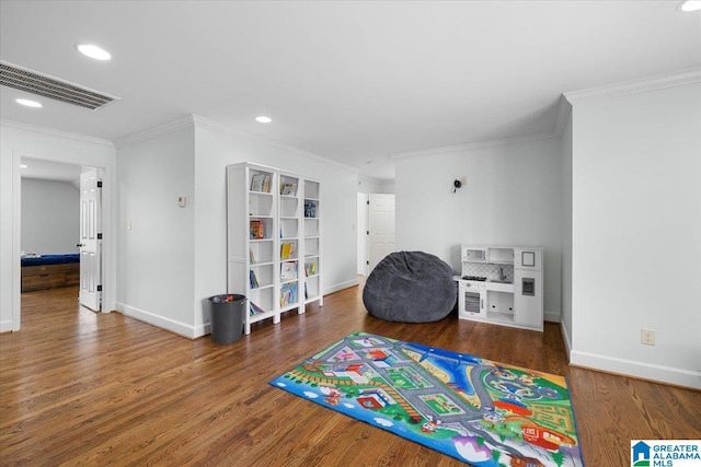 recreation room with visible vents, baseboards, crown molding, and wood finished floors