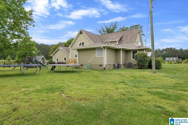view of property exterior featuring a lawn, a trampoline, central AC, and crawl space