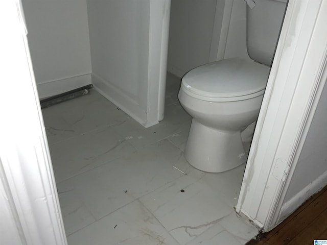 bathroom featuring toilet, baseboards, and marble finish floor
