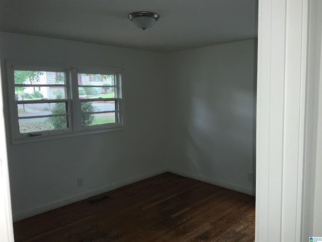 spare room featuring baseboards and dark wood-style flooring