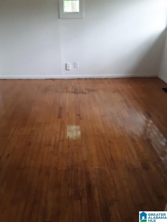 empty room with baseboards, wood-type flooring, and visible vents