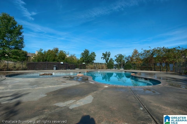 community pool featuring fence, a patio, and a jacuzzi
