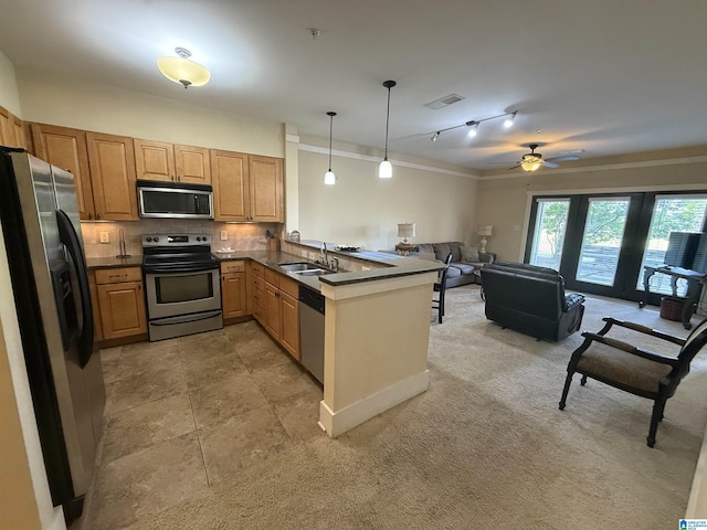 kitchen featuring appliances with stainless steel finishes, a sink, a peninsula, crown molding, and dark countertops