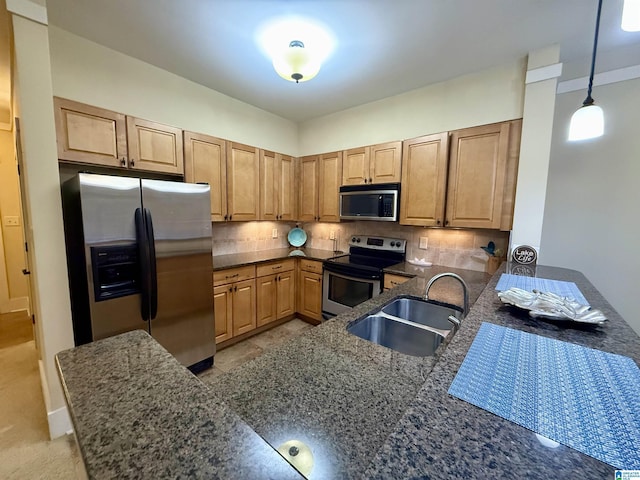 kitchen with stainless steel appliances, a sink, tasteful backsplash, dark stone countertops, and hanging light fixtures