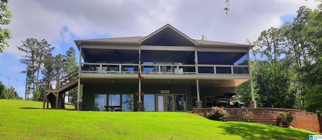 back of property featuring a lawn, stairs, a sunroom, and a deck