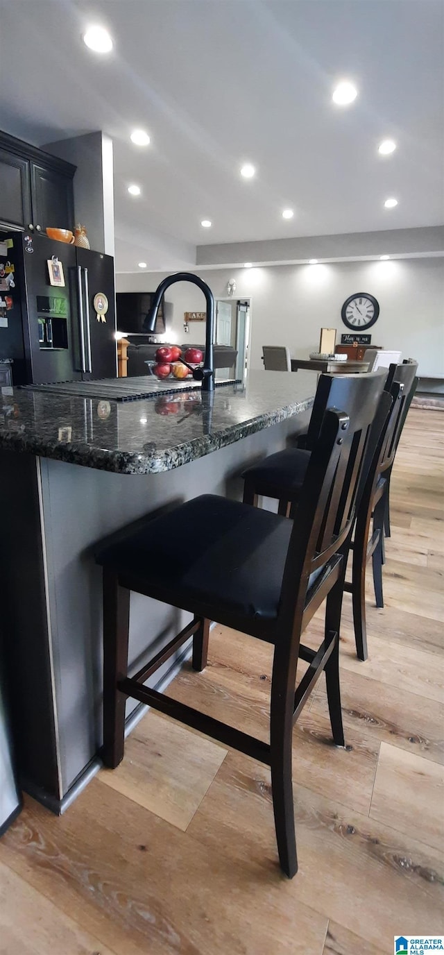 bar with recessed lighting, light wood finished floors, and black fridge with ice dispenser