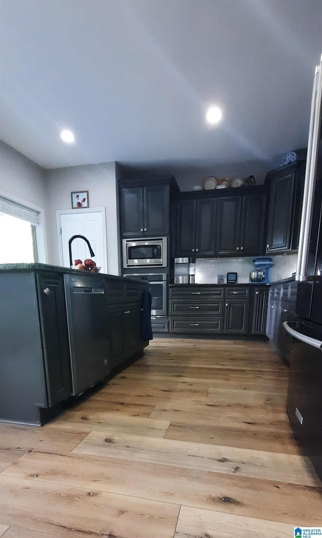kitchen with light wood-type flooring, recessed lighting, dark cabinetry, and stainless steel appliances