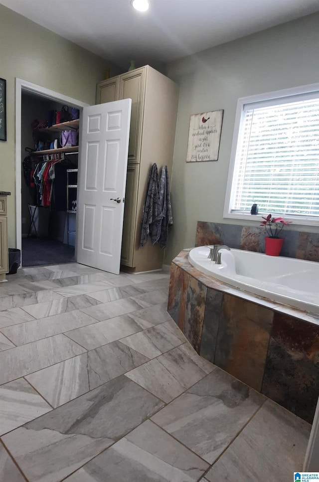 bathroom featuring a walk in closet and a bath