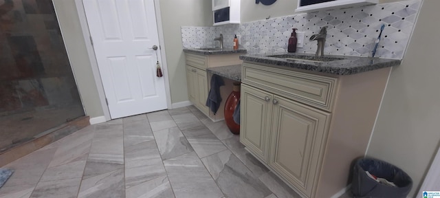 interior space with open shelves, decorative backsplash, cream cabinets, a sink, and dark stone countertops