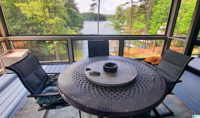 sunroom / solarium featuring outdoor dining area and a water view