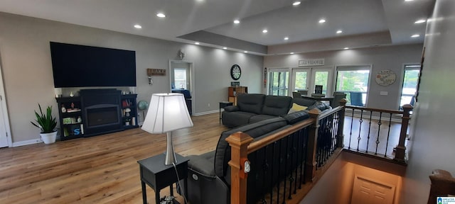 living room with recessed lighting, baseboards, wood finished floors, and a tray ceiling