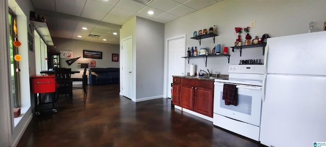 kitchen featuring concrete flooring, baseboards, reddish brown cabinets, recessed lighting, and white appliances