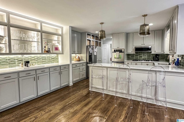kitchen featuring appliances with stainless steel finishes, a sink, dark wood-type flooring, backsplash, and gray cabinetry