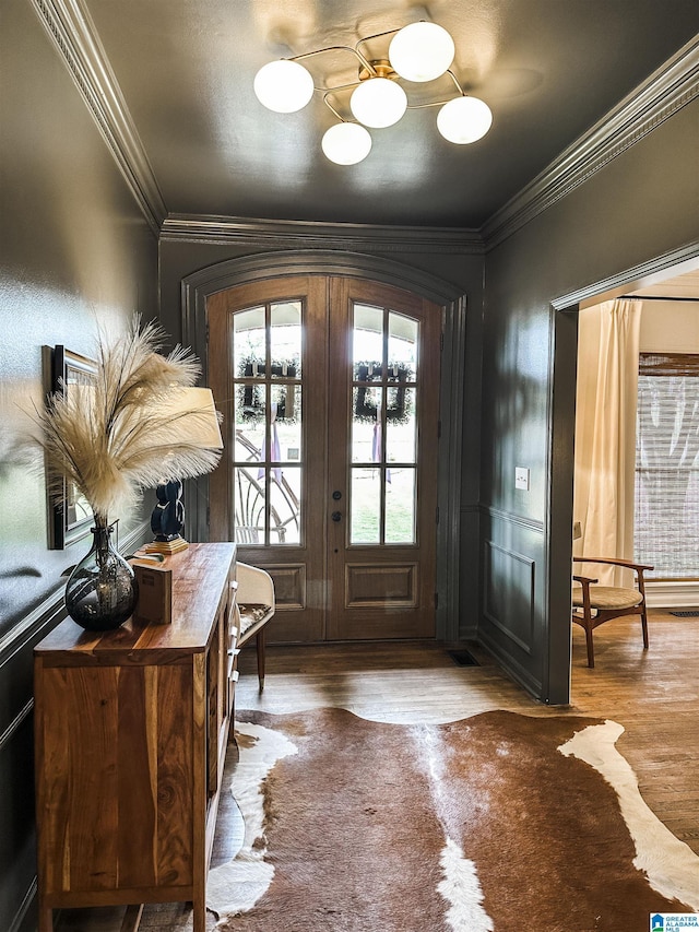 doorway featuring ornamental molding, wood finished floors, and a chandelier