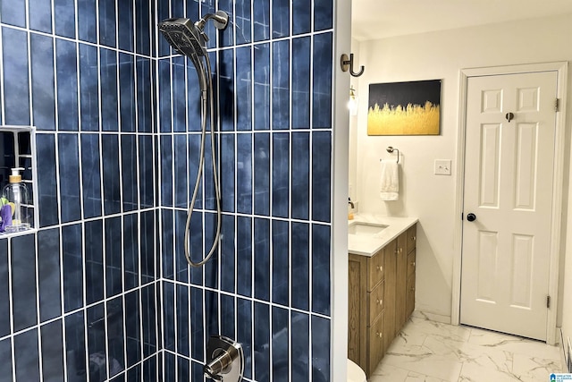 bathroom featuring tiled shower, marble finish floor, and vanity