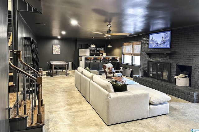 living room with ceiling fan, a fireplace, and concrete floors