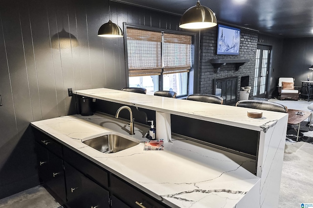 kitchen featuring dark cabinetry, open floor plan, a sink, and a fireplace