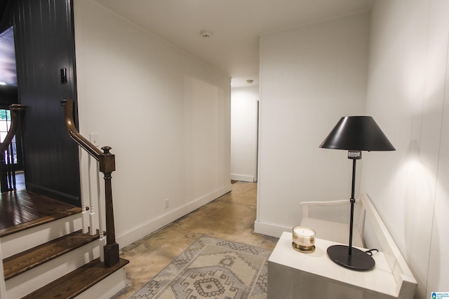 hallway with finished concrete floors, baseboards, and stairs