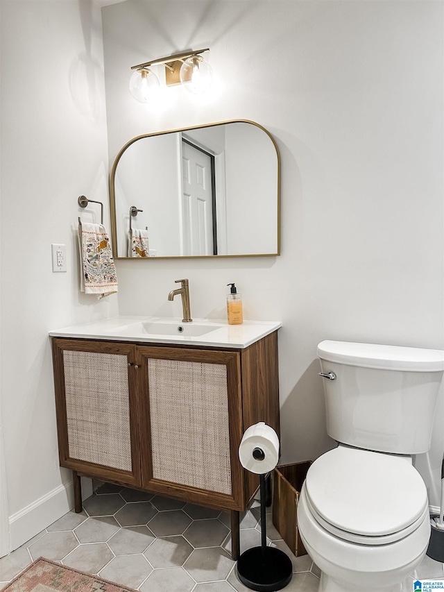 bathroom featuring toilet, tile patterned floors, baseboards, and vanity