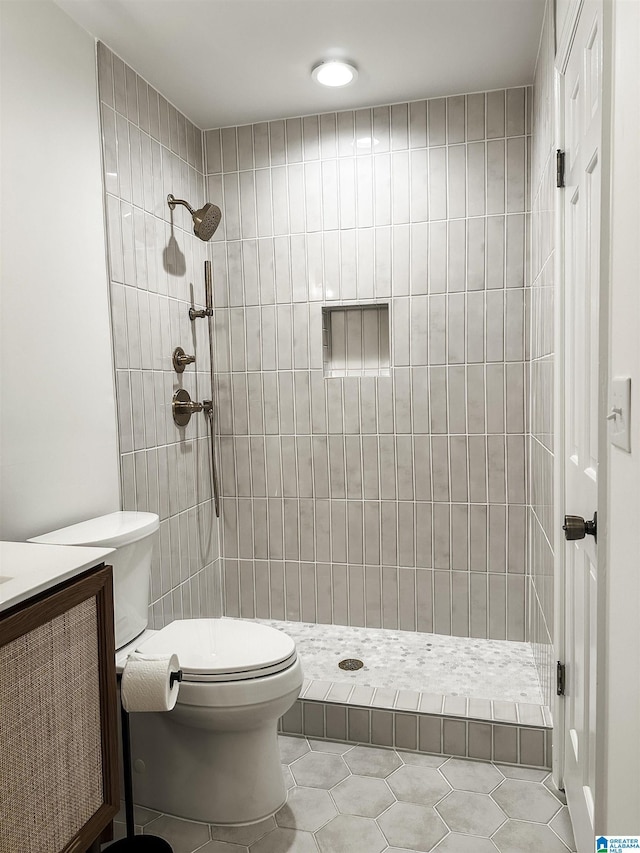 full bathroom featuring vanity, tile patterned floors, toilet, and tiled shower