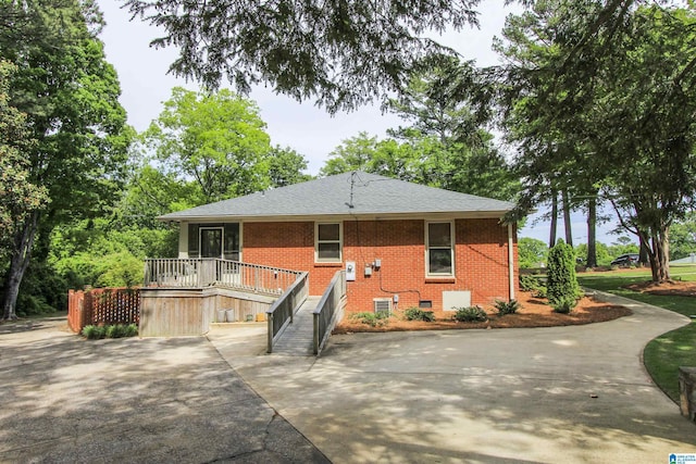 back of house with roof with shingles, crawl space, and brick siding