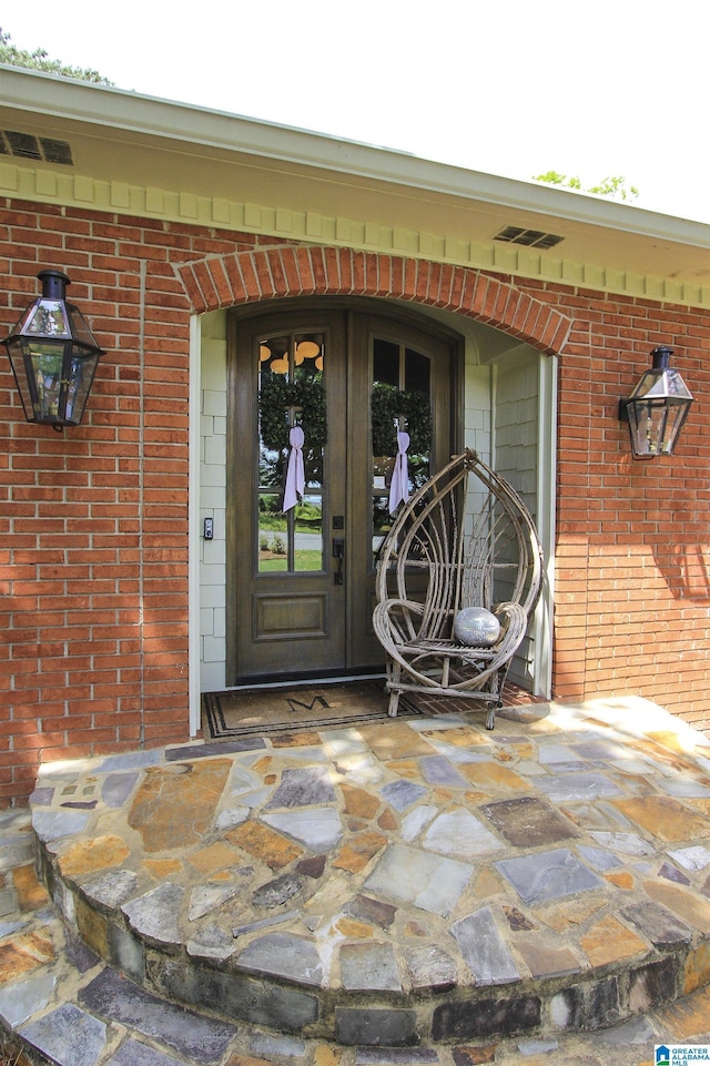 property entrance with brick siding and visible vents