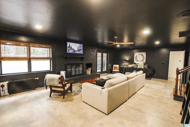 living area featuring a ceiling fan, concrete floors, a brick fireplace, and a wealth of natural light