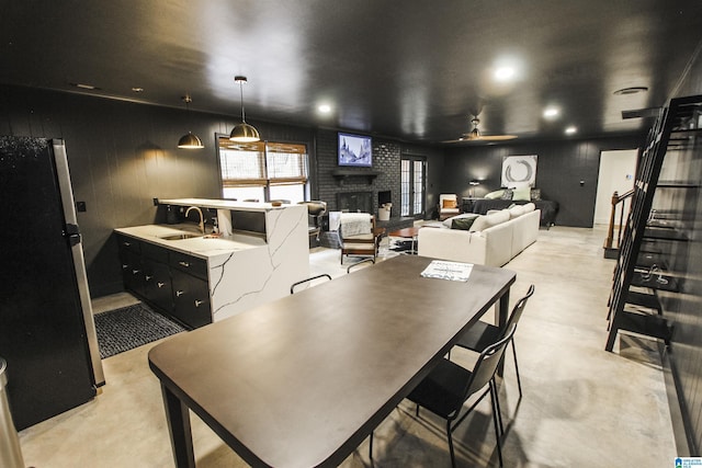 dining room with ceiling fan, a brick fireplace, stairway, concrete floors, and recessed lighting