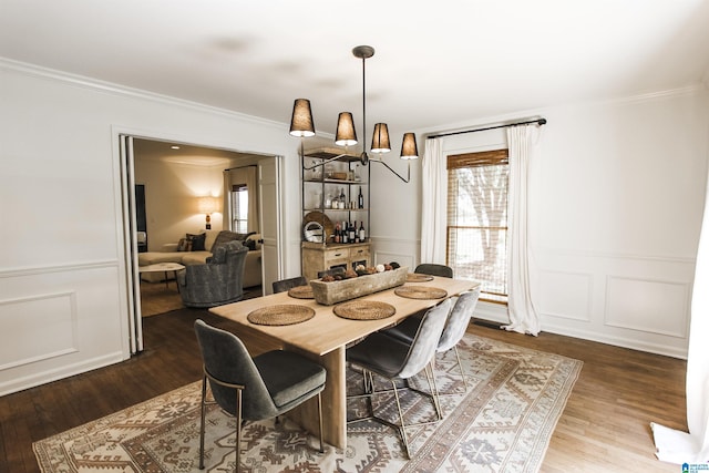 dining room with crown molding, a decorative wall, and wood finished floors