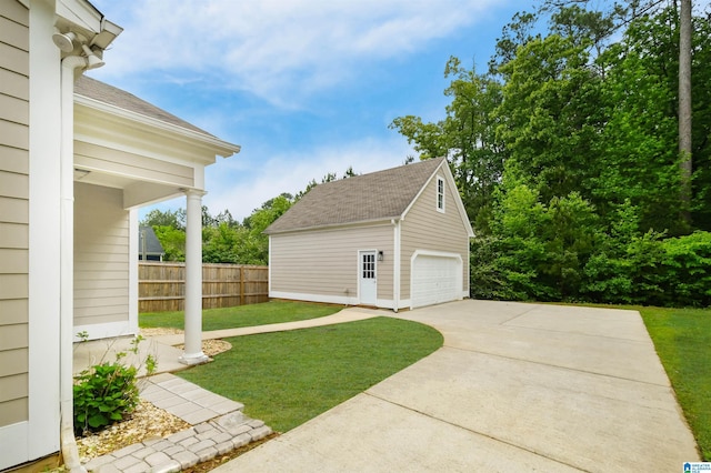 view of yard featuring a detached garage, fence, and an outbuilding