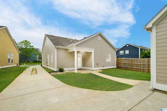 back of house featuring a lawn, a patio, fence, and driveway
