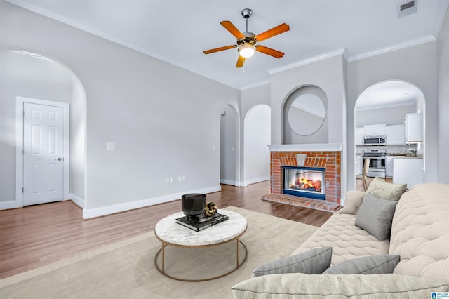 living area with visible vents, arched walkways, ceiling fan, and wood finished floors