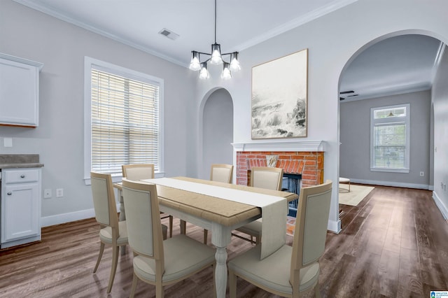 dining room featuring crown molding, arched walkways, baseboards, visible vents, and dark wood-style floors