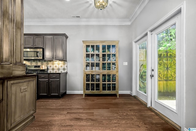 bar with crown molding, tasteful backsplash, stainless steel microwave, dark wood-type flooring, and visible vents