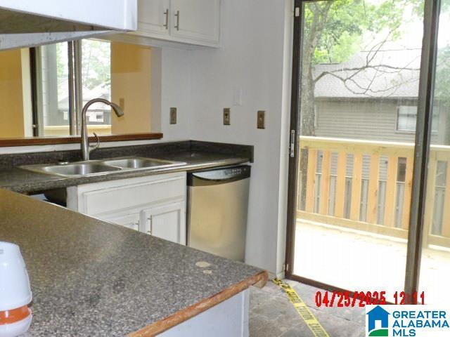 3821 Windhover Cir Unit 6, Vestavia Hills, AL 35216 - kitchen featuring dark countertops, plenty of natural light, white cabinetry, a sink, and dishwasher