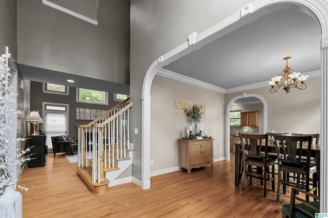 interior space featuring light wood finished floors, arched walkways, a chandelier, stairs, and ornamental molding