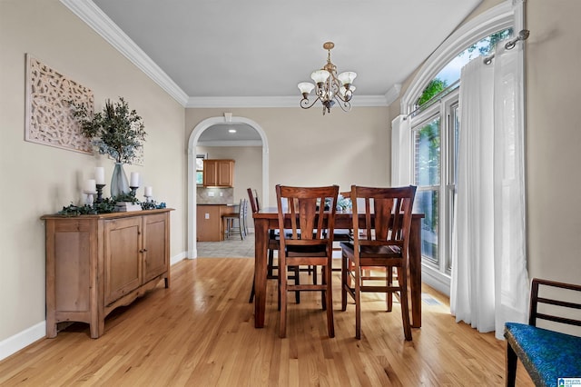 dining space featuring light wood-type flooring, arched walkways, a chandelier, and ornamental molding