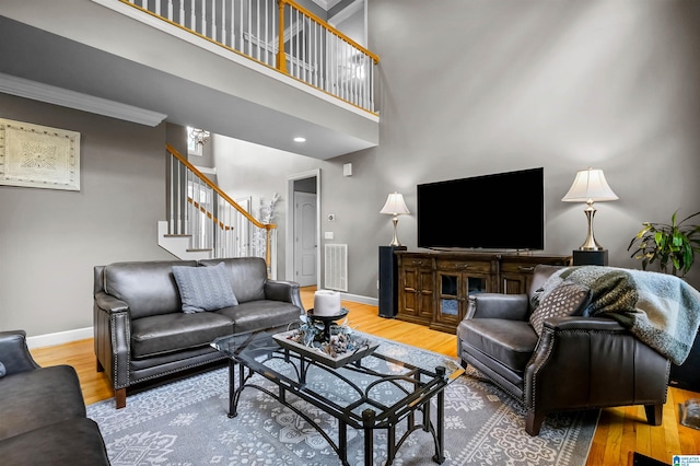 living room featuring baseboards, visible vents, wood finished floors, and stairway