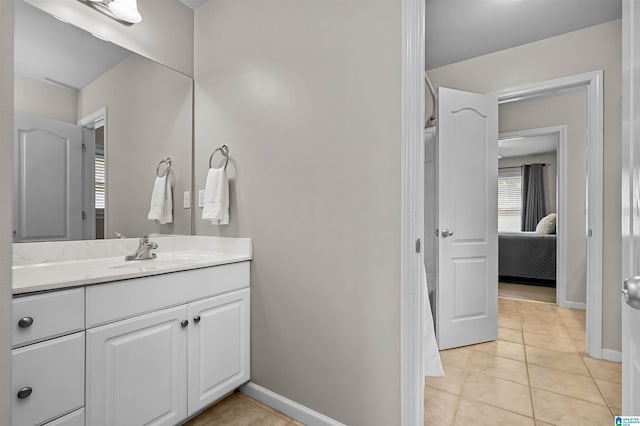 ensuite bathroom featuring baseboards, tile patterned flooring, vanity, and connected bathroom