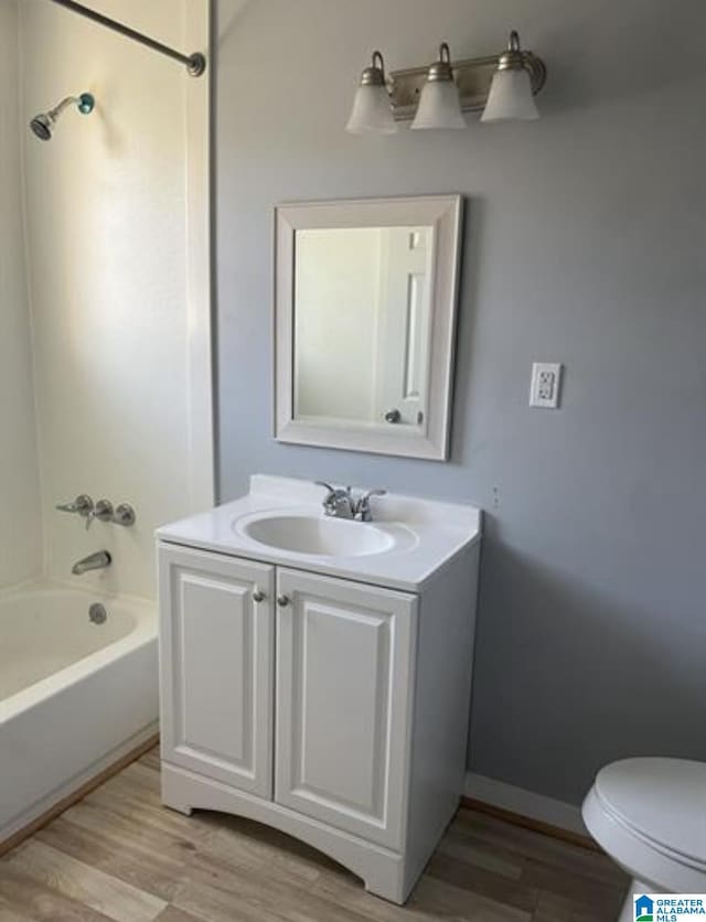 2129 Northland Ave SW, Birmingham, AL 35211 - bathroom featuring washtub / shower combination, vanity, toilet, baseboards, and wood finished floors