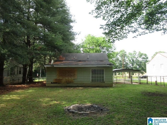 rear view of property featuring fence, a yard, and a carport