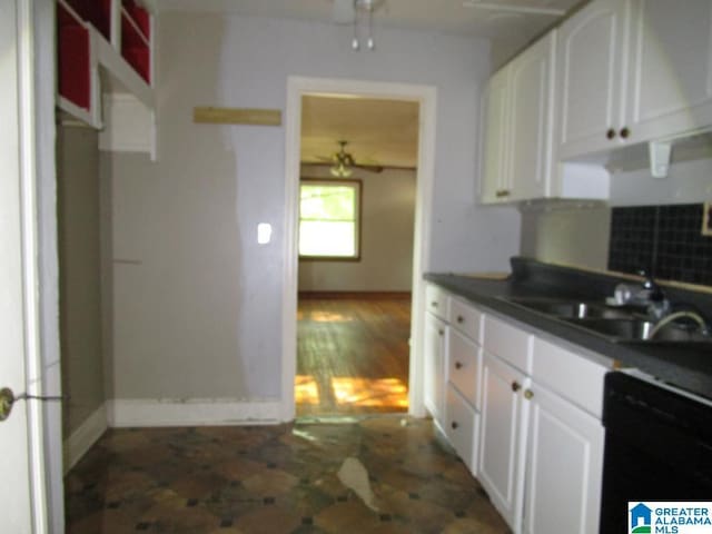kitchen with a ceiling fan, dark countertops, a sink, black dishwasher, and white cabinetry