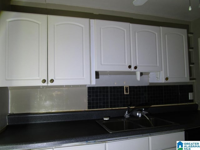 kitchen featuring a sink, white cabinets, dark countertops, and tasteful backsplash