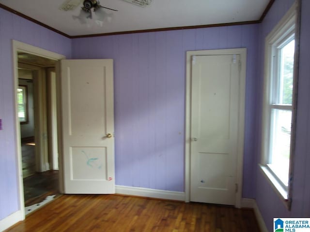 unfurnished bedroom with baseboards, ornamental molding, and wood finished floors