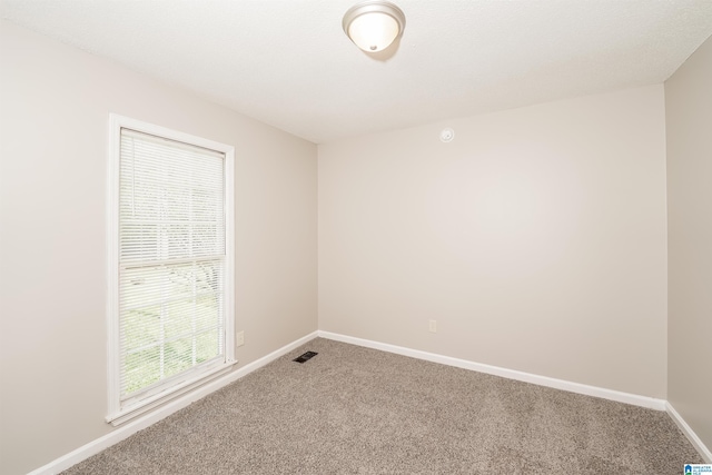 carpeted spare room featuring baseboards and visible vents